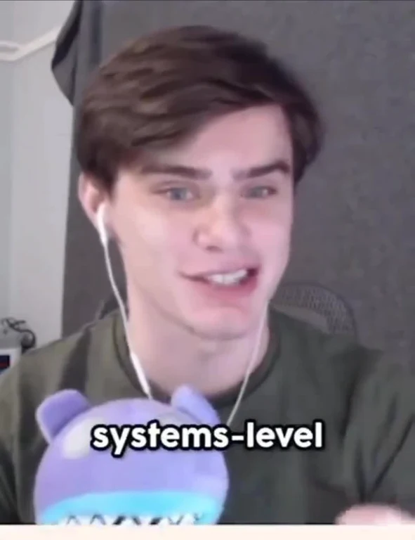 a man smiling and holding a purple toy with the text 'systems-level'