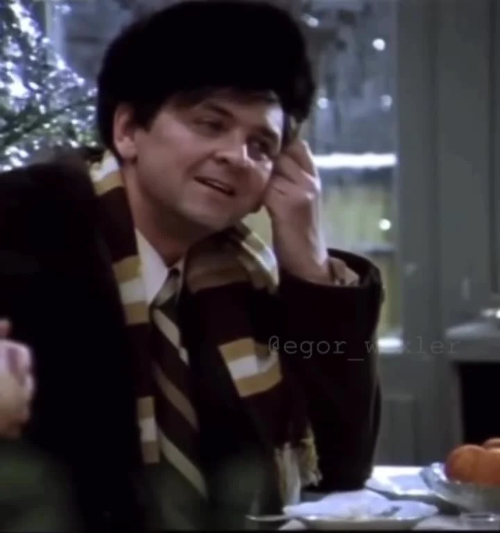 Man in striped scarf smiling and looking pleased