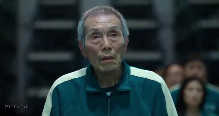 Close-up of the elderly man in a green tracksuit from Squid Game looking shocked and confused.