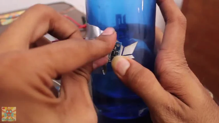 Close-up of hands holding a small electronic circuit board and a blue cylindrical component