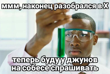man in lab goggles holding up a test tube