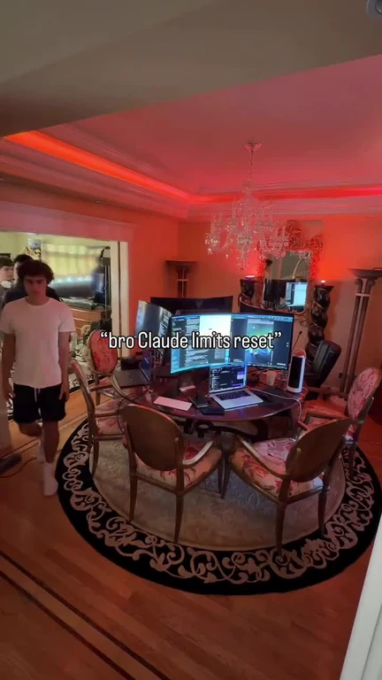 A young man walks into a red-lit luxury dining room with a chandelier and a multi-monitor dev setup on the table, captioned 'bro Claude limits reset'