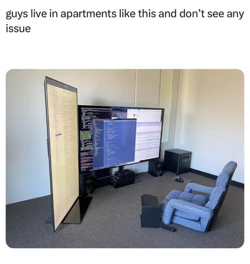 a recliner and a desk with multiple computer monitors