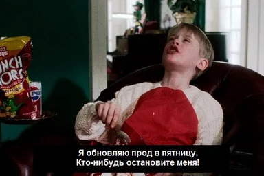 Boy laughing in a chair with a red pillow, looking up, with a bag of chips on the side and text in Russian about updating prod on Friday