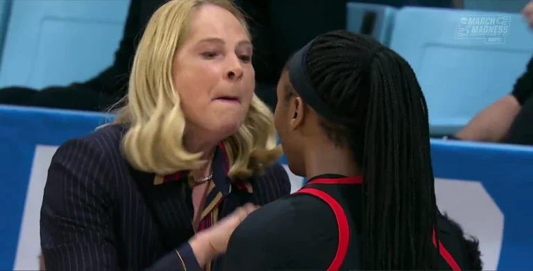 Two women talking intensely, one in a business suit and the other in a sports jersey