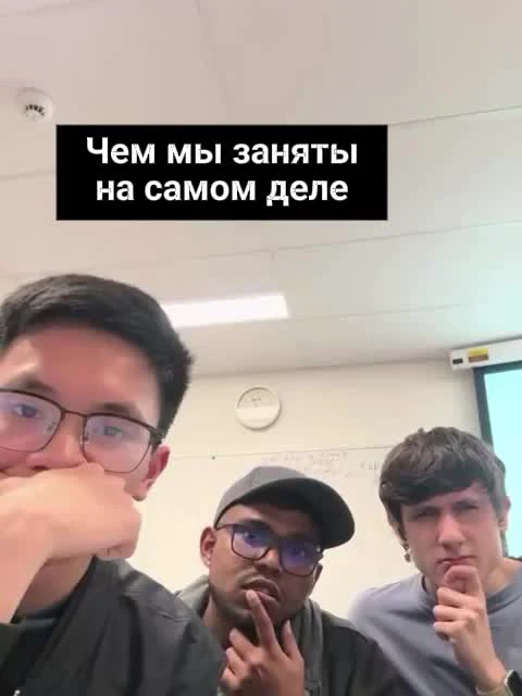 Three men in a meeting or classroom setting with a caption in Russian