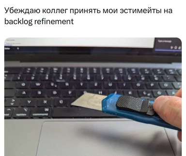 a hand holding a blue utility knife with a gray grip in front of a laptop keyboard