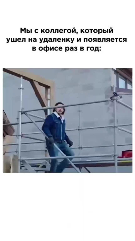 Man in a blue jacket walking on scaffolding with a serious expression