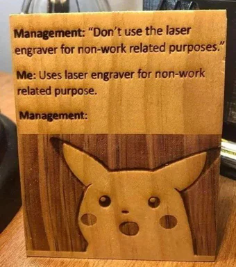 Wooden block with laser-engraved text about non-work usage and a surprised Pikachu face.