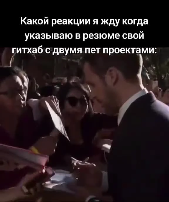 a man in a suit signing autographs with a crowd around him