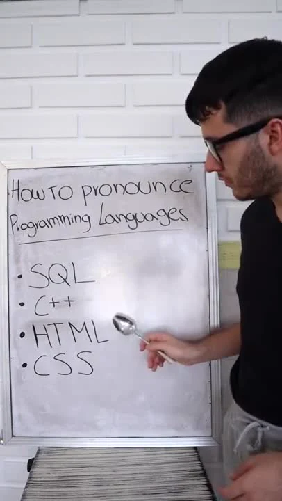 man looking at whiteboard with programming language pronunciation guide