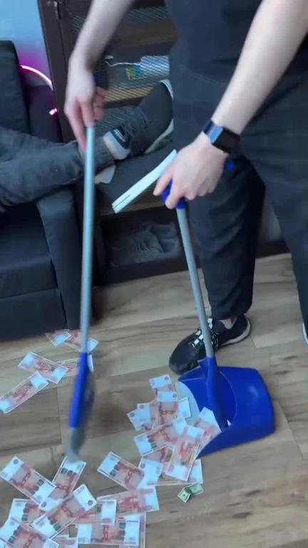 Person sweeping scattered euro banknotes on the floor with a broom and blue dustpan