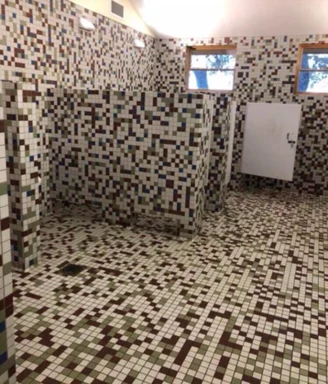 A bathroom with walls and floor covered in mosaic tiles arranged to look like a pixelated 8-bit map.