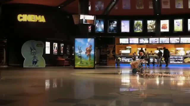 Bugs Bunny and Wile E. Coyote standing in a cinema lobby with a pile of cash on the floor