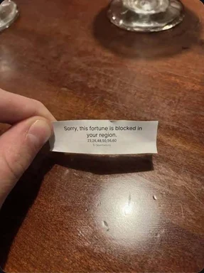 Hand holding a fortune cookie slip that says 'Sorry, this fortune is blocked in your region' with IP numbers.