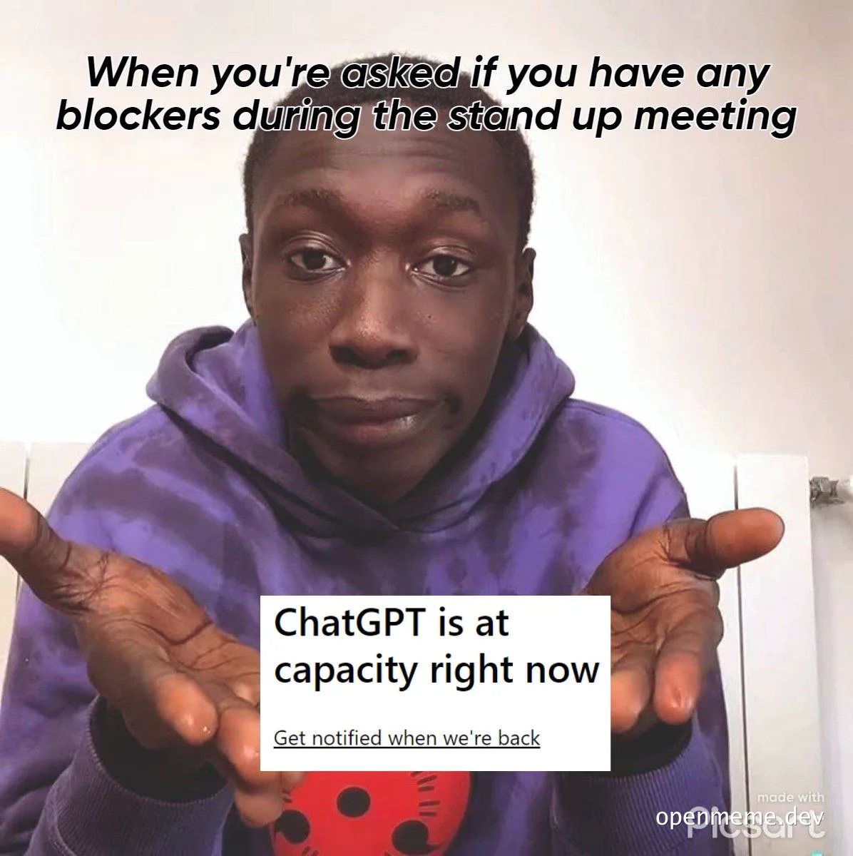 Man in purple hoodie shrugs with text 'When you're asked if you have any blockers during the stand up meeting' and 'ChatGPT is at capacity right now'