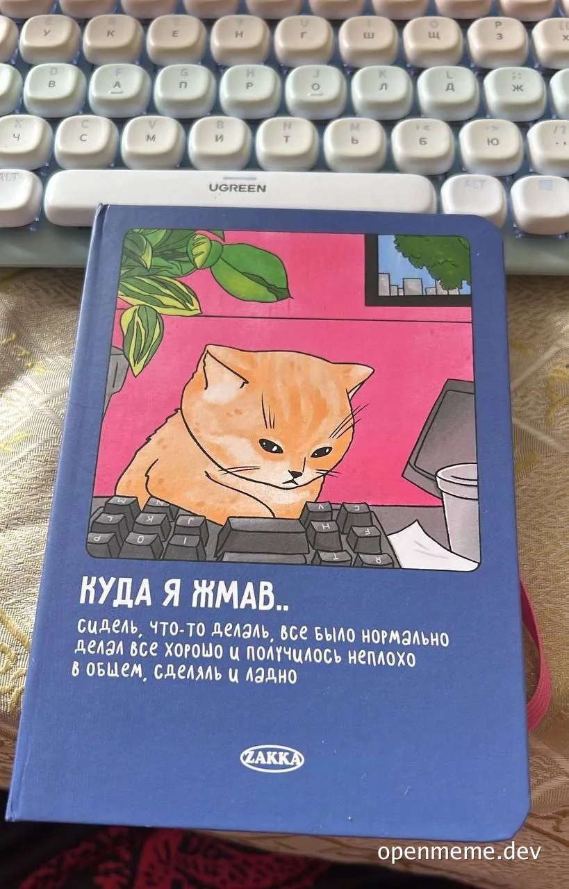 A blue notebook with a cartoon orange cat sitting at a computer keyboard on the cover, with Russian text.