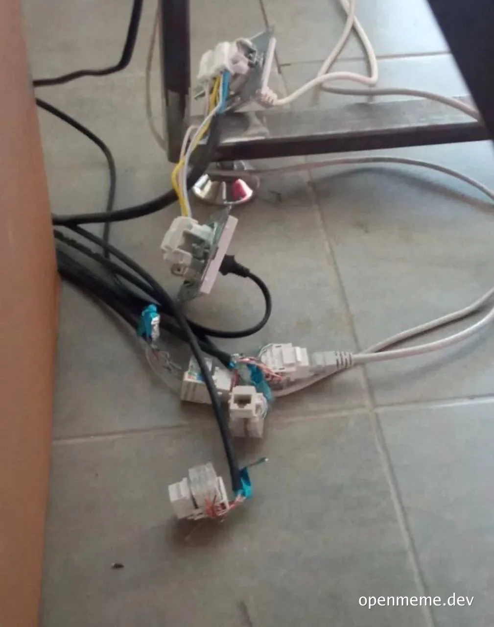 a mess of wires and cables on a tiled floor