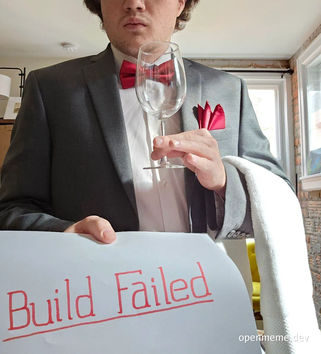 man in suit holding wine glass and sign with 'Build Failed' written on it