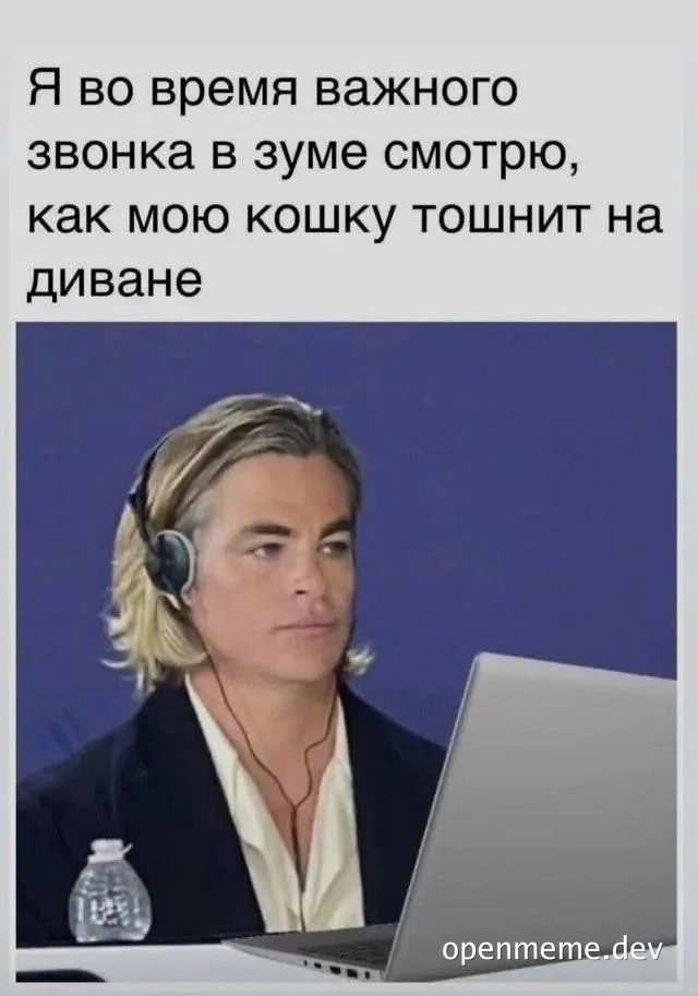 Man in a suit with headphones on during a video call while looking at his cat vomiting on the couch