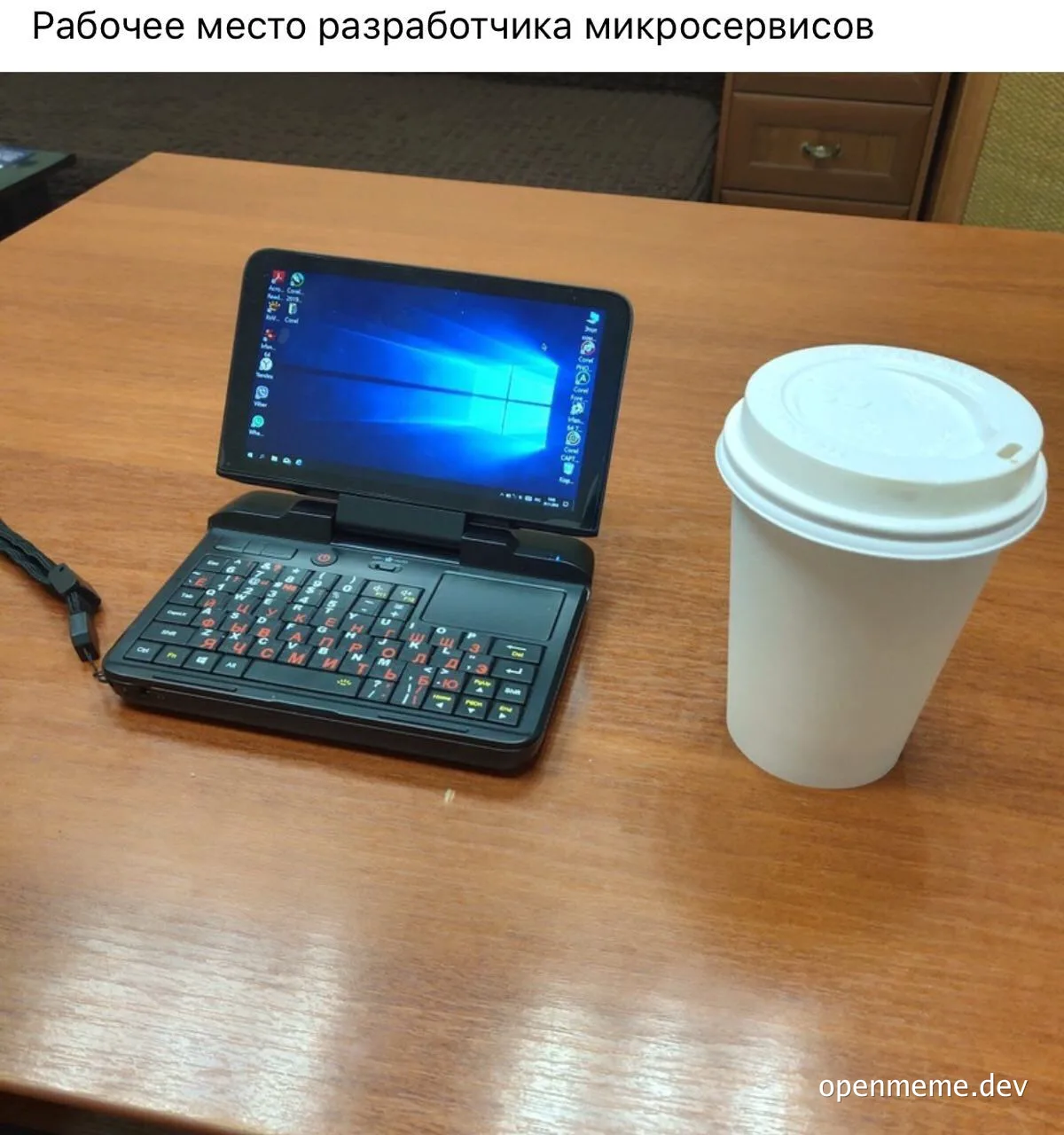a laptop with russian keyboard and a coffee cup on a desk