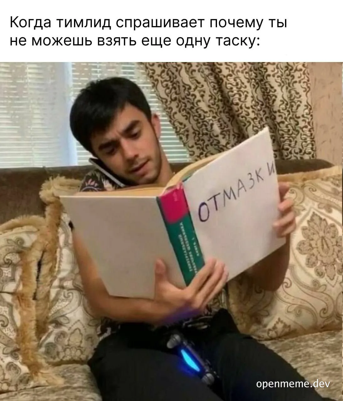 a man sitting on a couch holding a book with 'отмазки' written on it