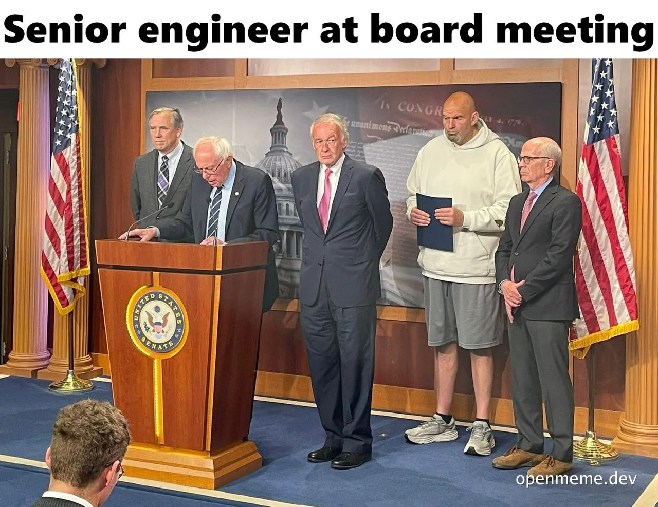 senior engineer in casual clothes at a formal board meeting with politicians