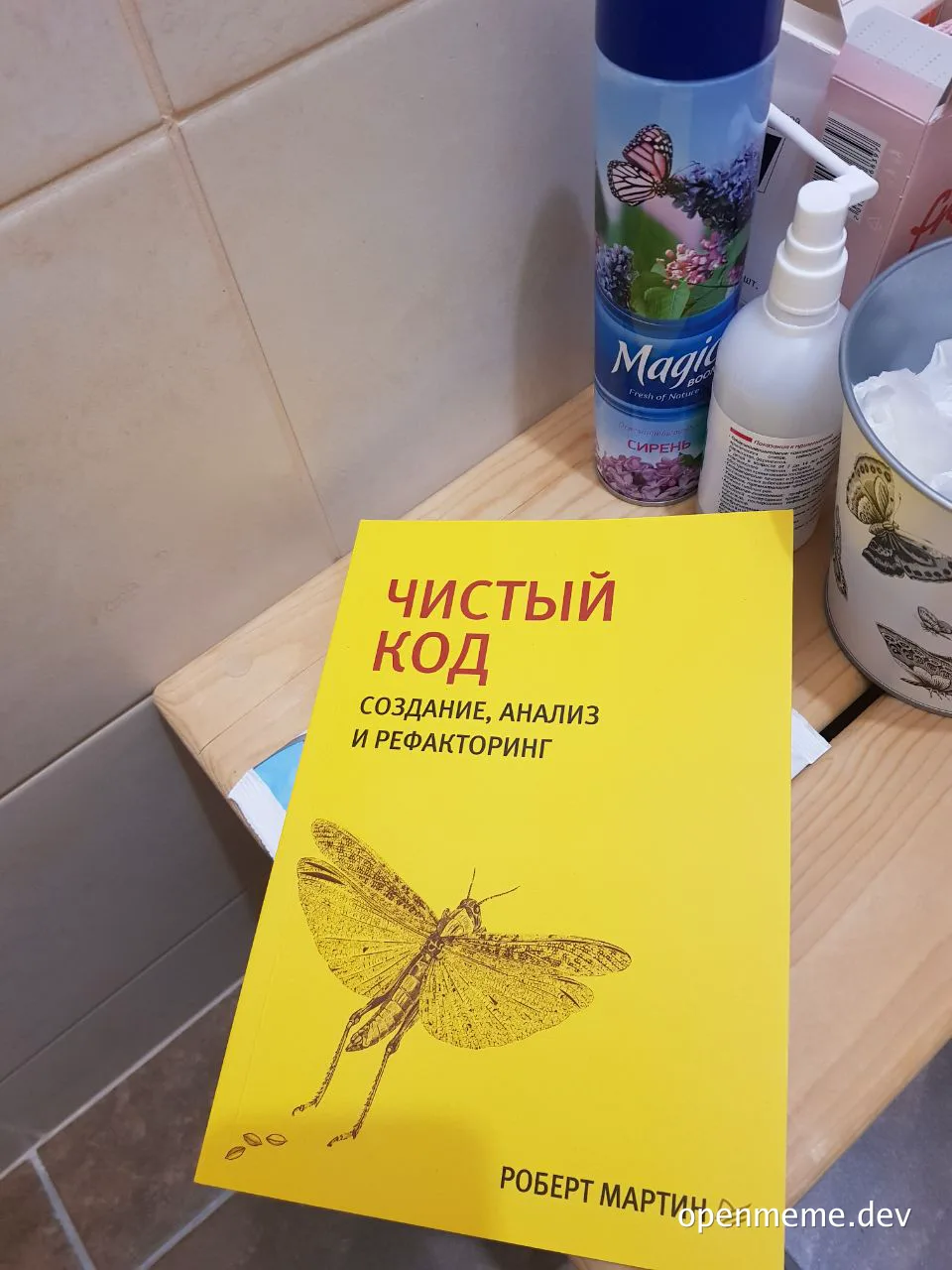 A yellow book titled 'Чистый код' by Robert Martin on a bathroom counter
