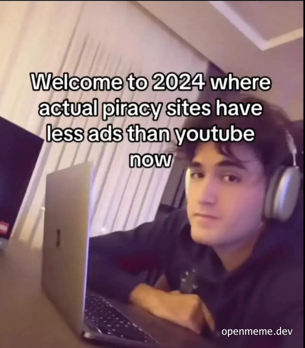 a man wearing headphones sits at a laptop with a look of dismay on his face