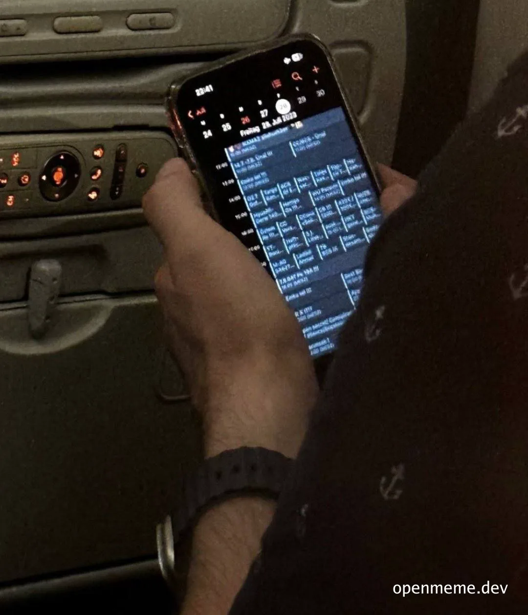 person holding phone with schedule on screen in airplane