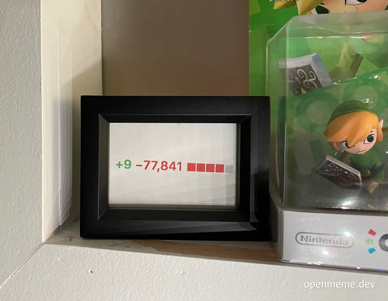 framed note with green plus 9 and red minus 77841 next to Link figurine