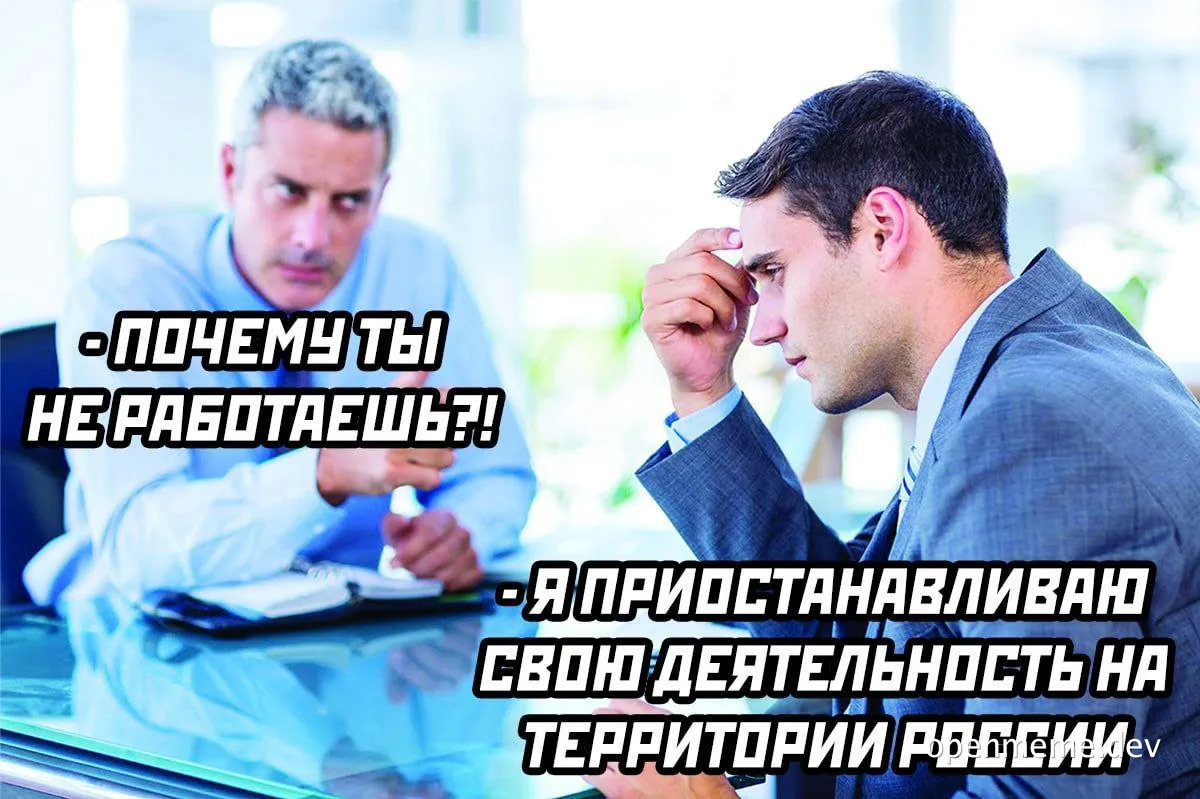 Two men in business attire sitting at a desk with a frustrated expression