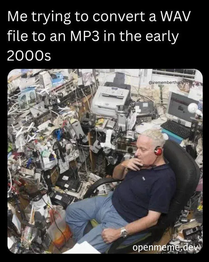 Man sitting in a chair surrounded by a chaotic pile of old computer and electronic junk, looking puzzled while wearing headphones.