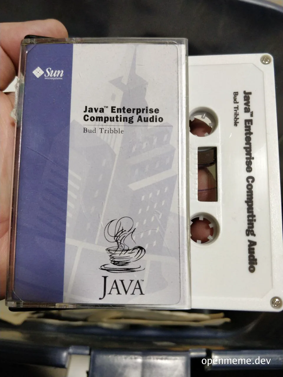A hand holding a cassette tape labeled 'Java Enterprise Computing Audio' by Bud Tribble.