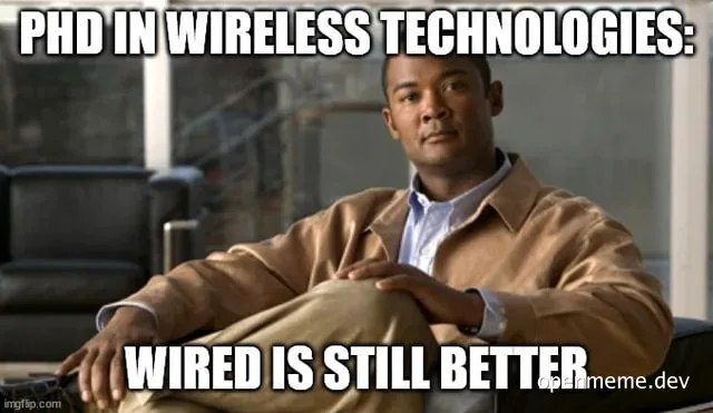 Man sitting with arms crossed, looking smug, with text 'PHD IN WIRELESS TECHNOLOGIES: WIRED IS STILL BETTER'