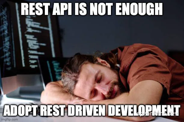programmer sleeping at desk with computer screens in background