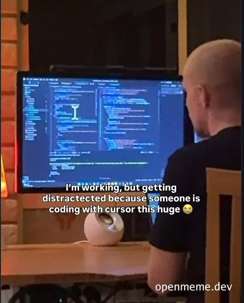 Bald man sitting at desk getting distracted from coding by someone with oversized cursor
