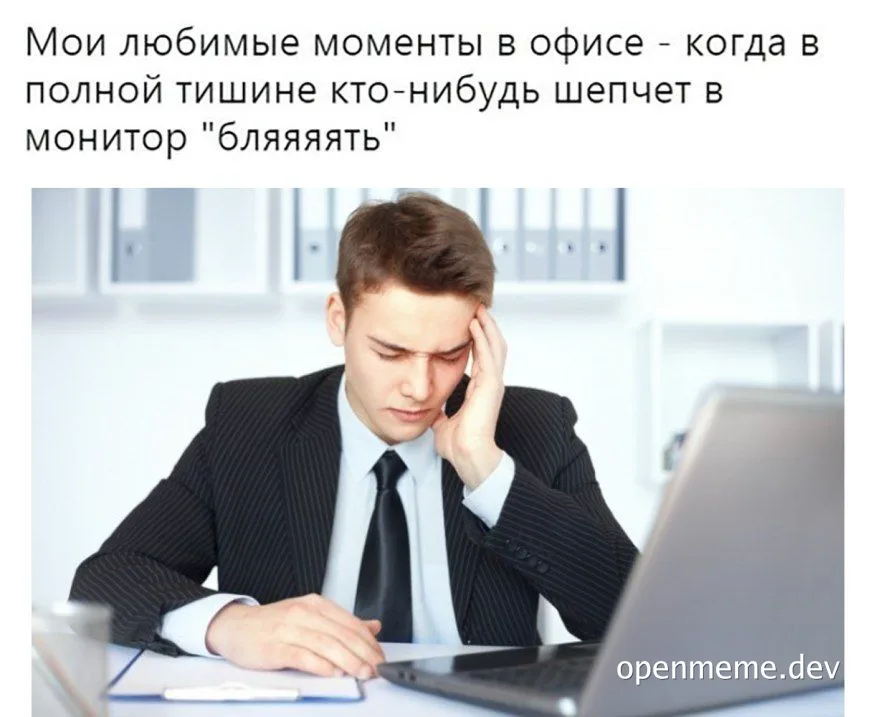 Man in suit sitting at desk with laptop, rubbing temples in frustration