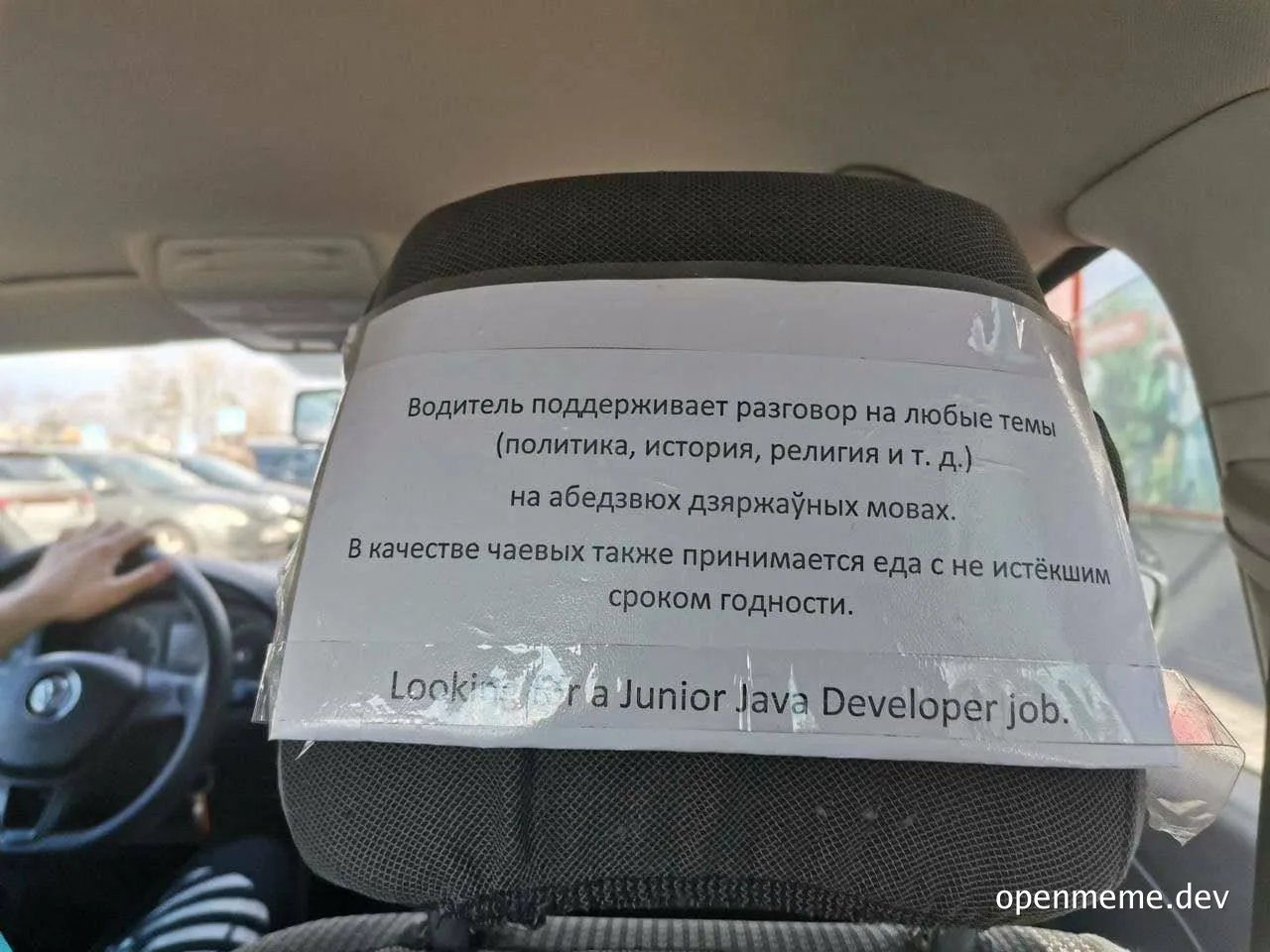 A humorous sign on a car headrest reading 'Looking for a Junior Java Developer job' with text in Russian above it.