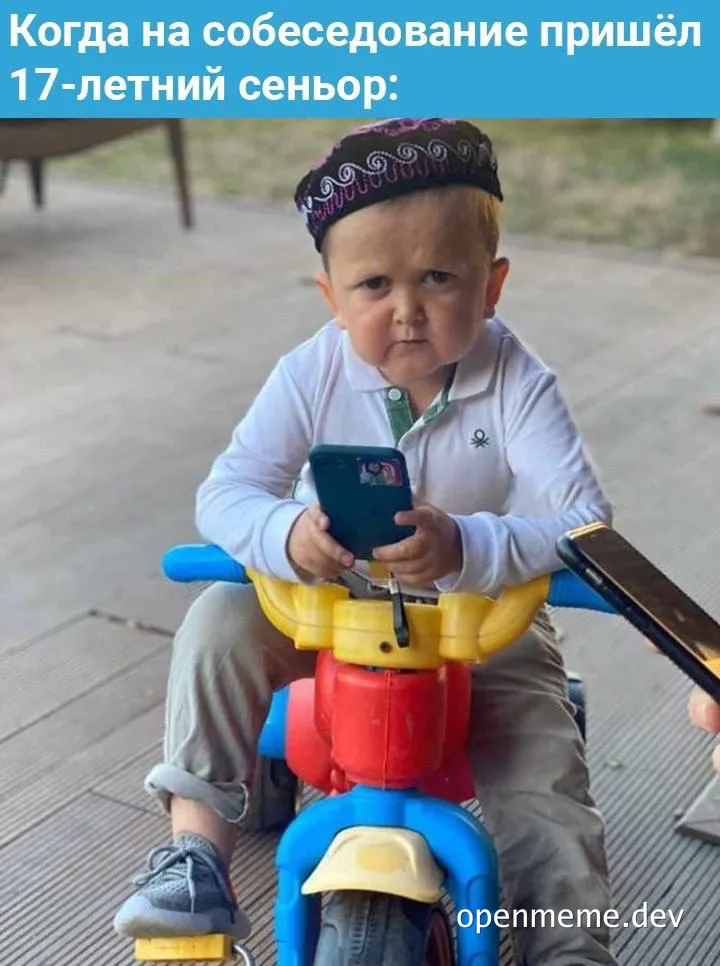 a young boy sitting on a tricycle looking at a smartphone with a caption about a 17-year-old senior dev
