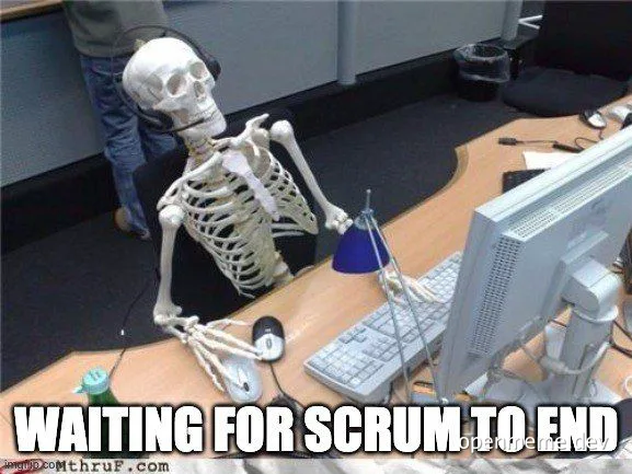 A skeleton sitting at a desk with a computer, waiting for scrum to end