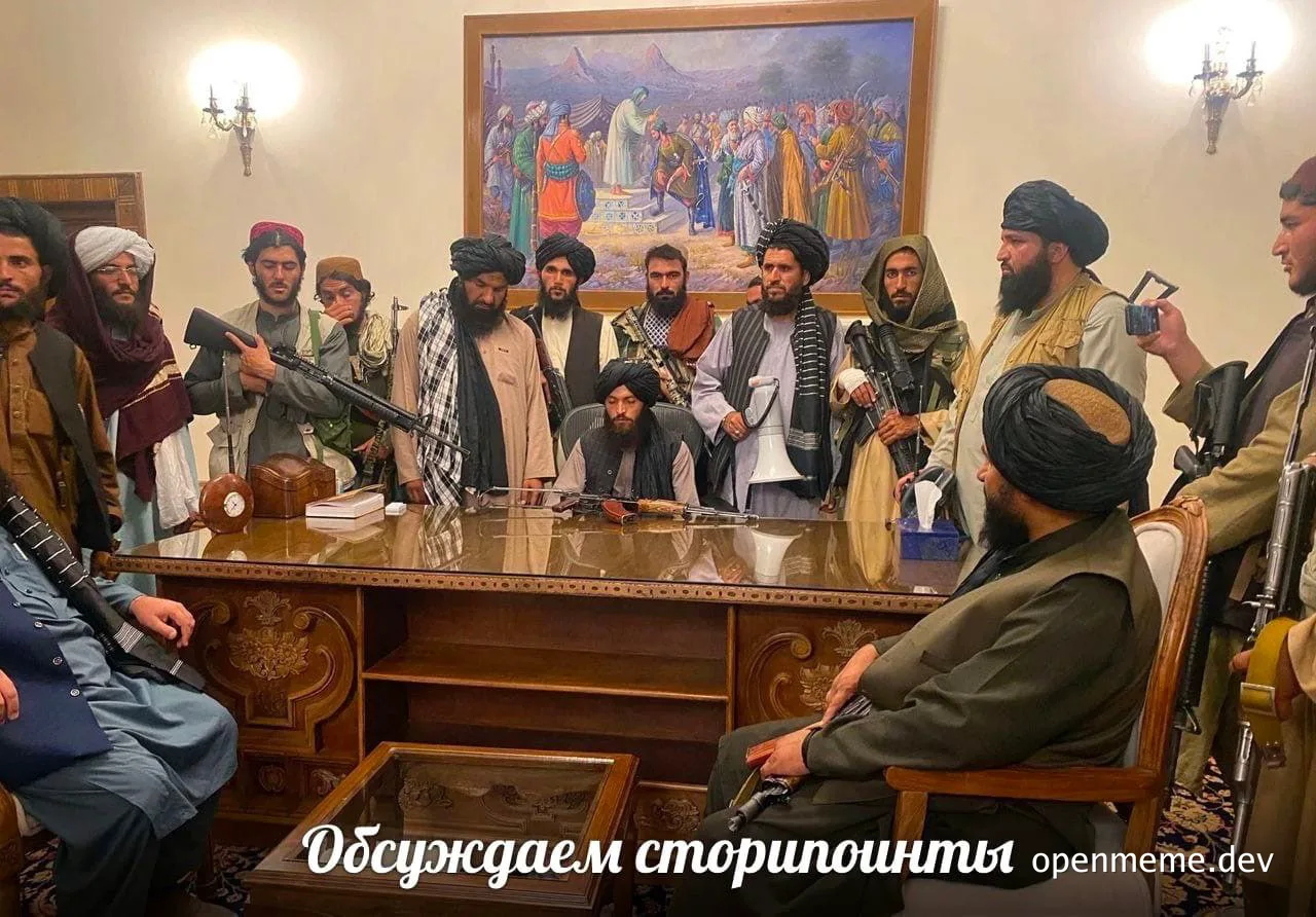 Armed men in traditional clothing gathered around a large wooden desk